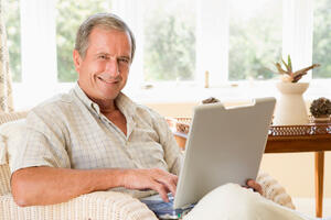 Man smiling holding a laptop